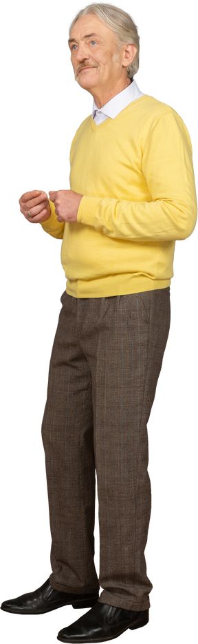 Dreiviertelansicht eines alten lächelnden mannes, der gelben pullover trägt und hände zusammenstellt