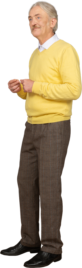 Three-quarter view an old smiling man wearing yellow pullover and putting hands together