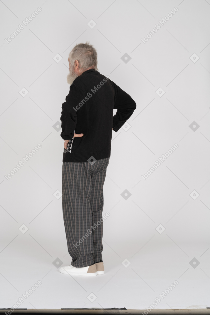 Side view of an elderly man standing with his hands on his hips