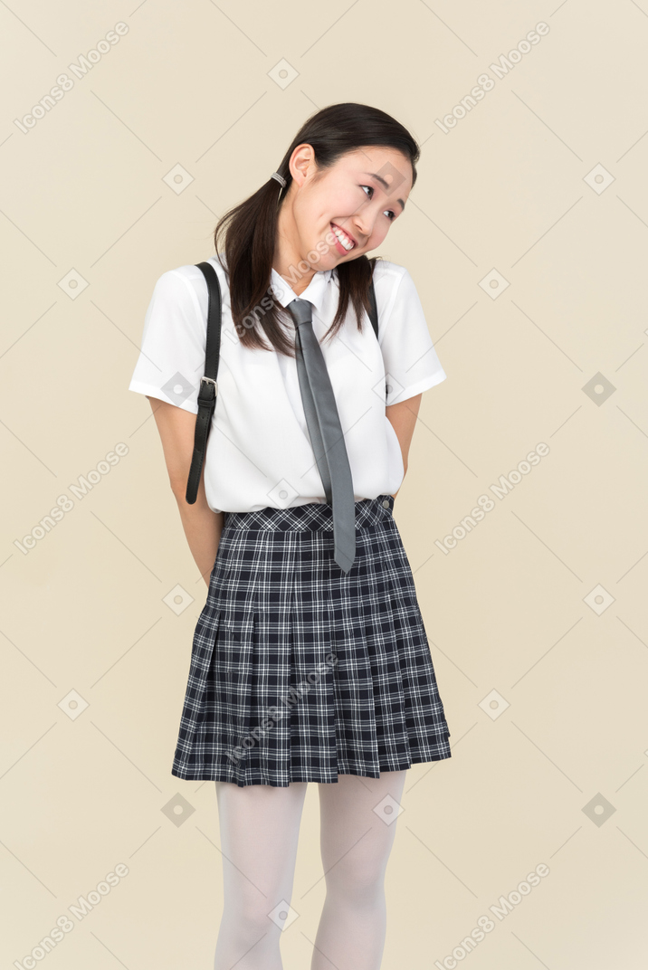 Shy asian school girl holding hands behind back