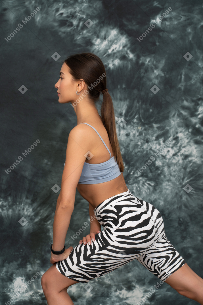 Vista lateral de una atleta femenina haciendo una estocada