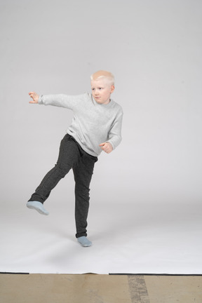 Front view of boy in casual clothes kicking his leg