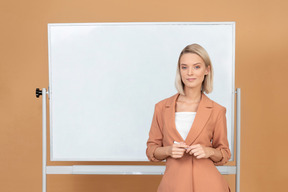 Attraktive junge frau, die etwas nahe dem whiteboard erklärt