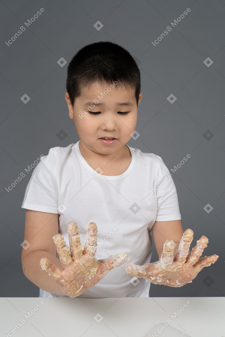 A surprised little boy looking at his floury hands