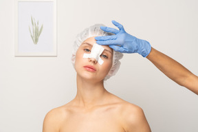 Nurse applying bandage to female patient's nose