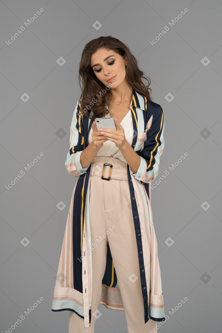 Безэмоциональная молодая женщина, использующая мобильный телефон для текстовых сообщений