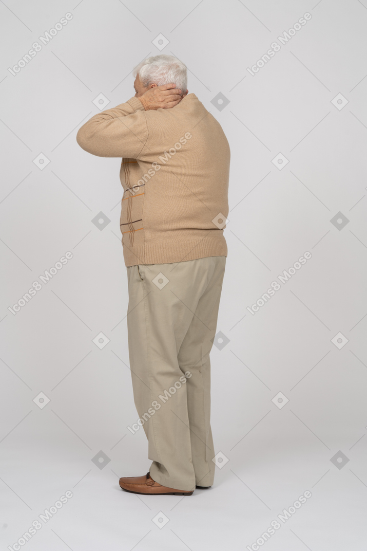 首に手を置いて立っているカジュアルな服装の老人の側面図