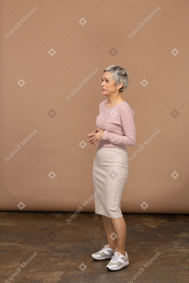 Расстроенная женщина в повседневной одежде стоя в профиль
