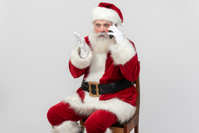 Surprised santa claus sitting and talking on the phone