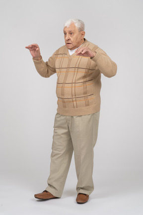 Vista frontal de un anciano con ropa informal asustando a alguien