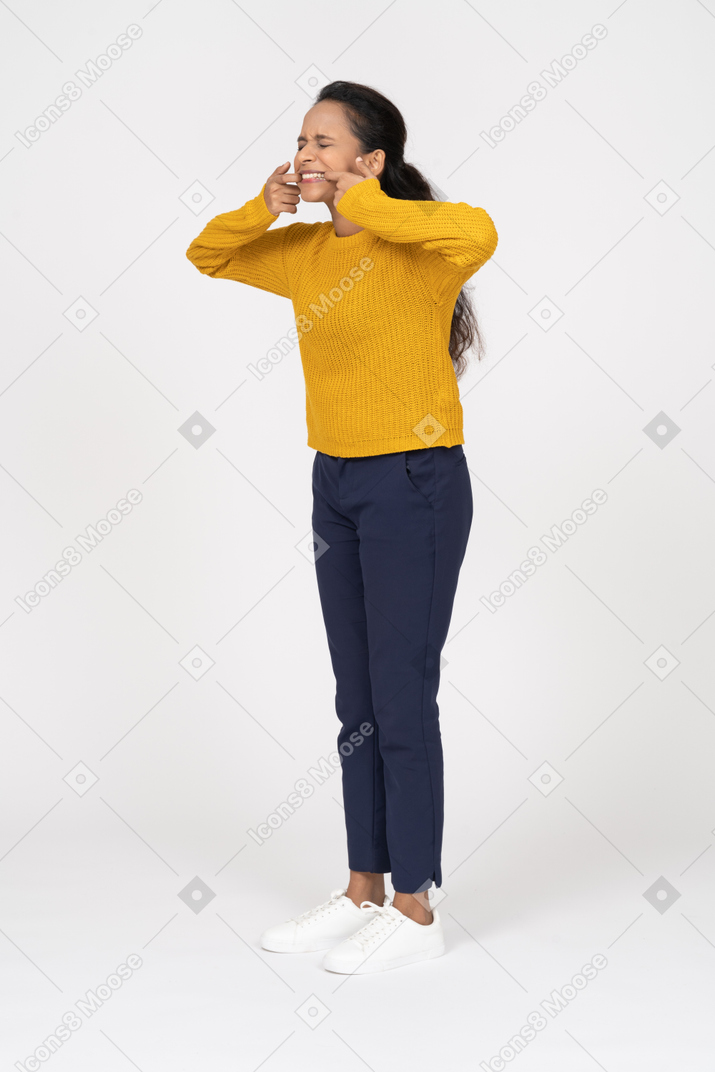 Vista lateral de uma garota com roupas casuais colocando os dedos na boca