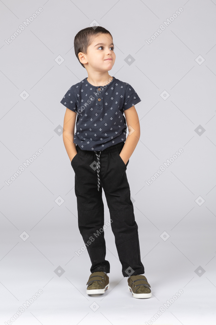 Вид спереди милый мальчик позирует с руками в карманах