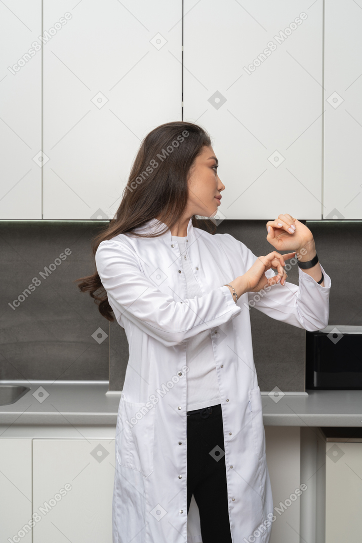 Woman in lab coat turning right and looking at smartwatch