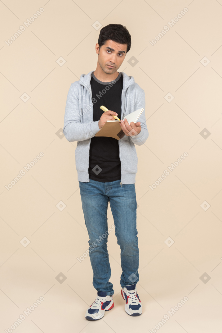 Young caucasian man writing in a notebook