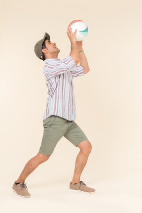 Young caucasian guy standing in profile and holding ball