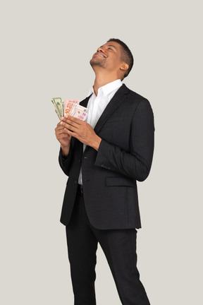 Vista de tres cuartos de un joven en traje negro sosteniendo billetes