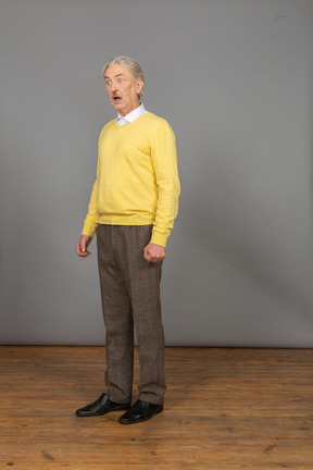 Vista di tre quarti di un uomo che parla in un pullover giallo con la bocca aperta