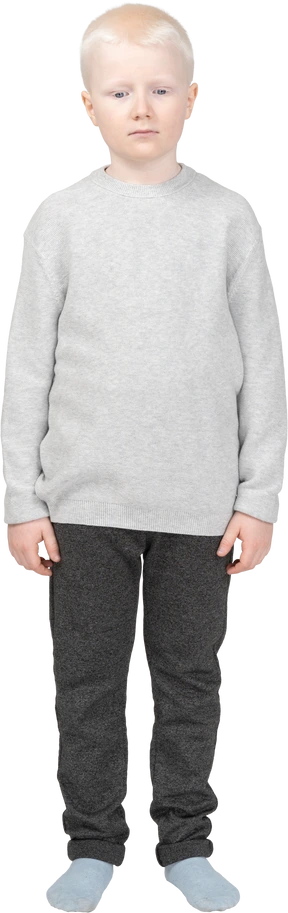 Front view of a blond little boy standing still and looking down