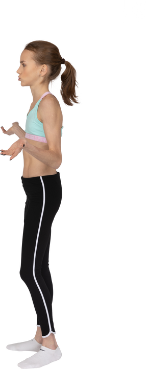 Side view of a perplexed teen girl in sportswear raising hands