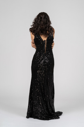 Woman in black evening dress hugging herself