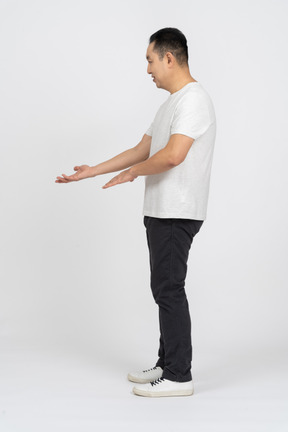 Вид сбоку на мужчину в повседневной одежде, стоящего с вытянутой рукой