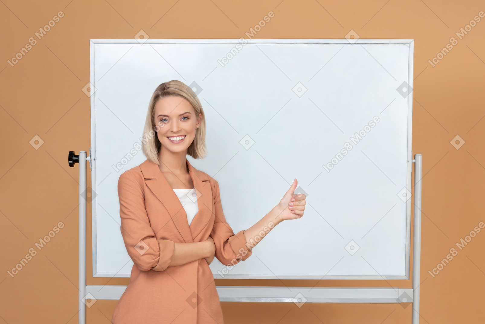 Lächelnde junge frau, die nahe bei einem whiteboard steht und sich einen daumen zeigt