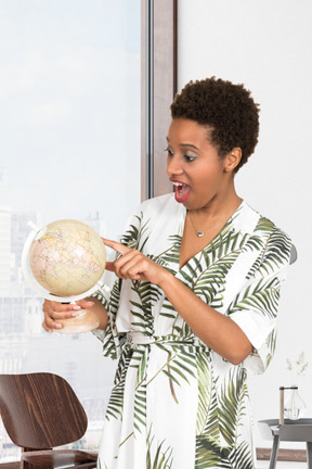 Excited young woman looking at her desk globe