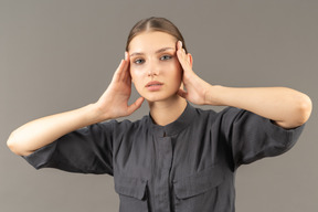 Front view of a young woman in a jumpsuit with clean skin touching face