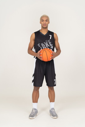 Front view of a young male basketball player holding a ball