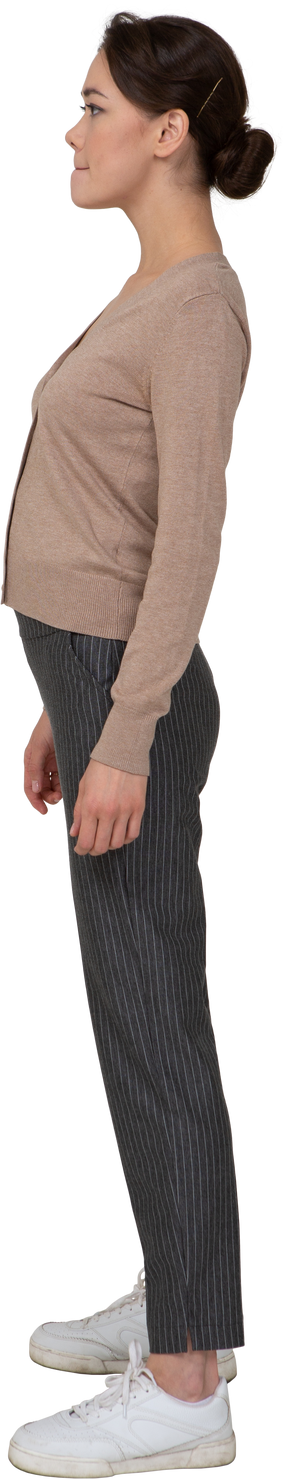 Vista lateral de uma mulher descontente em um pulôver e calças pressionando os lábios