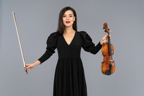 Front view of a female violin player in black dress making a bow