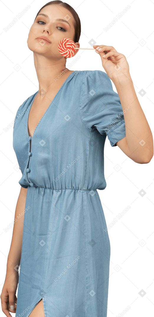Vue de trois quarts d'une jeune femme en robe bleue tenant une sucette