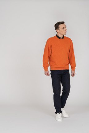 Junger mann im orangefarbenen sweatshirt zu fuß