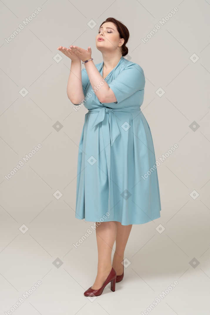 Vista frontal de uma mulher de vestido azul mandando um beijo