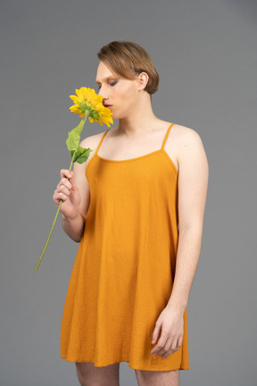 Front view of a genderqueer person smelling sunflower