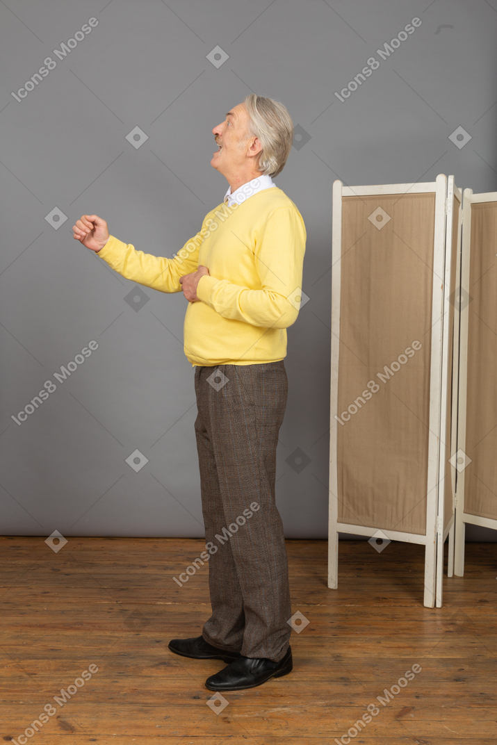 Side view of an inspired old man raising his hand