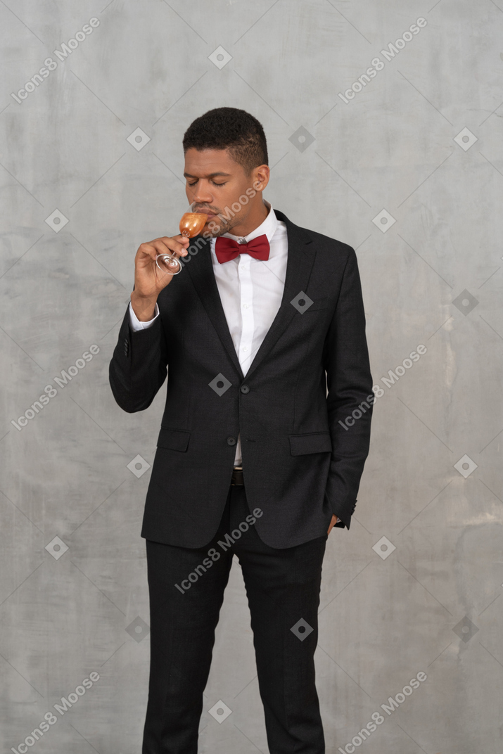 Jeune homme aux yeux fermés buvant dans un verre de champagne