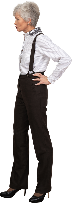 Side view of a displeased old lady in office clothing putting hands on hips
