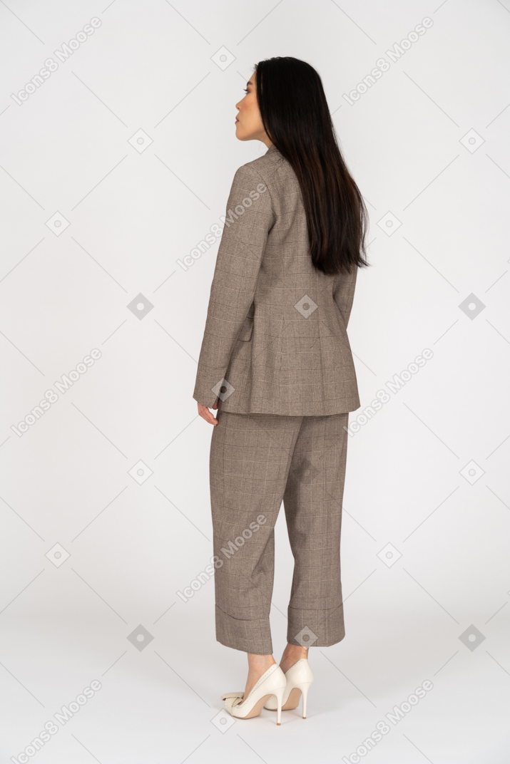 Three-quarter back view of a young lady in brown business suit leaning forward