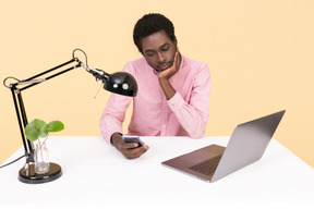 Handsome young man looking bored while using a phone