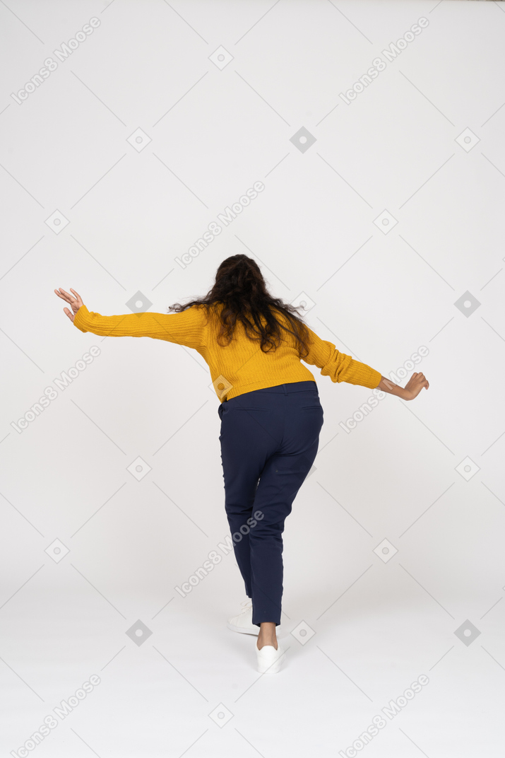 Rear view of a girl in casual clothes posing with outstretched arms
