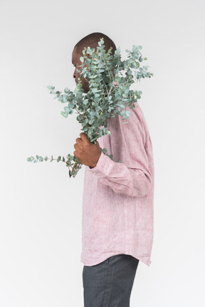 Good looking young man holding green branches