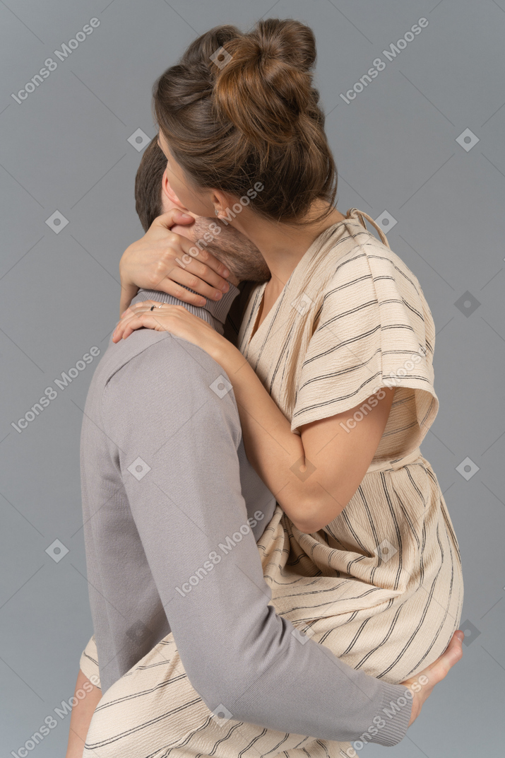 Мужчина держит свою девушку и целует ее