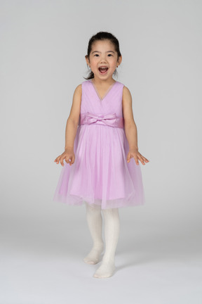 Bambina in un vestito dal tutù che posa giocosamente