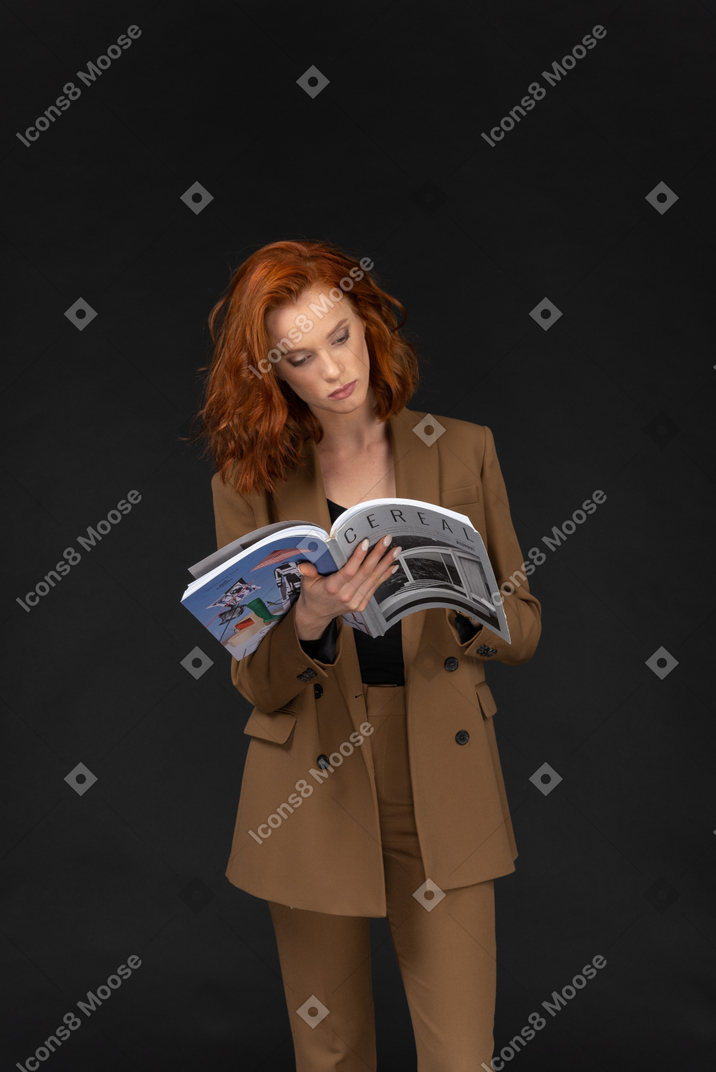 Vista frontal de una joven empresaria leyendo una revista
