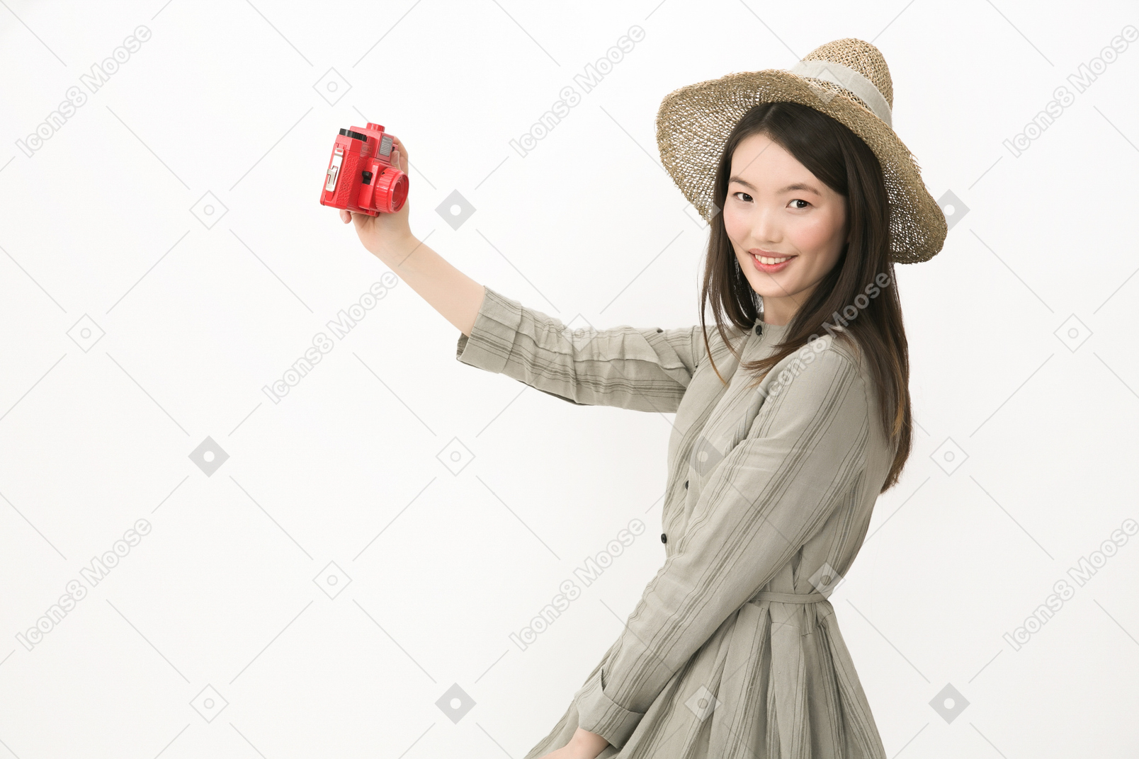 Gir in hat standing in profile and making a selfie with red camera