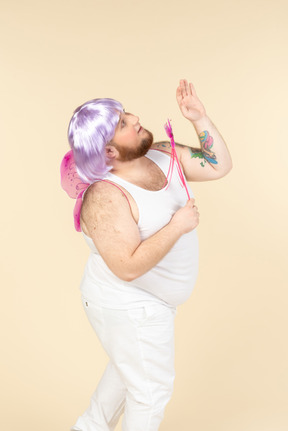 Dreamy young overweight man dressed as a fairy