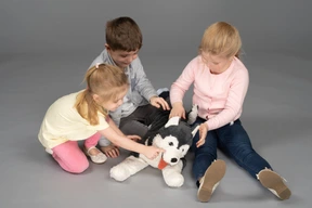 Tres niños lindos jugando con juguete husky