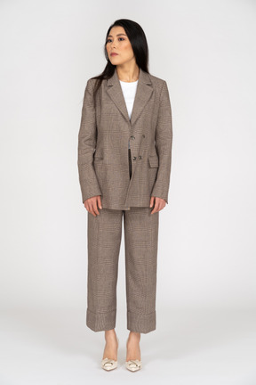 Front view of a young lady in brown business suit looking aside