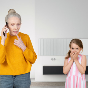 Old woman talking on the phone and surprised little girl covering her mouth